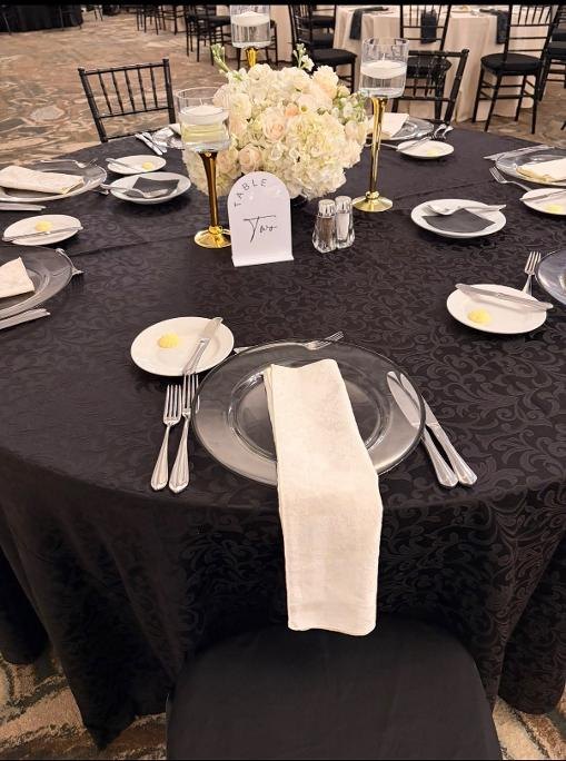 Black table linen with white floral centerpiece and gold candleholders