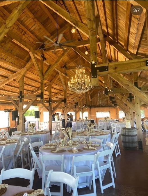 Rustic barn event venue with chandeliers and decorated round tables